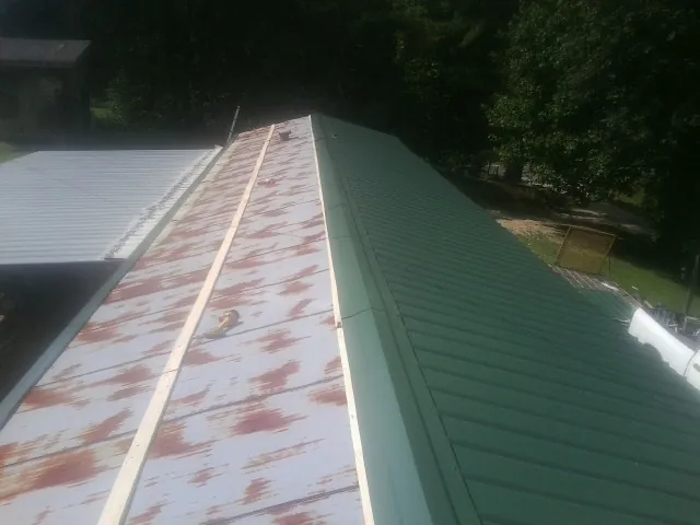 Old rusted panels beside newly installed green metal roofing — Wind Damage Roof Repair by Roofing Brothers in Bellvue