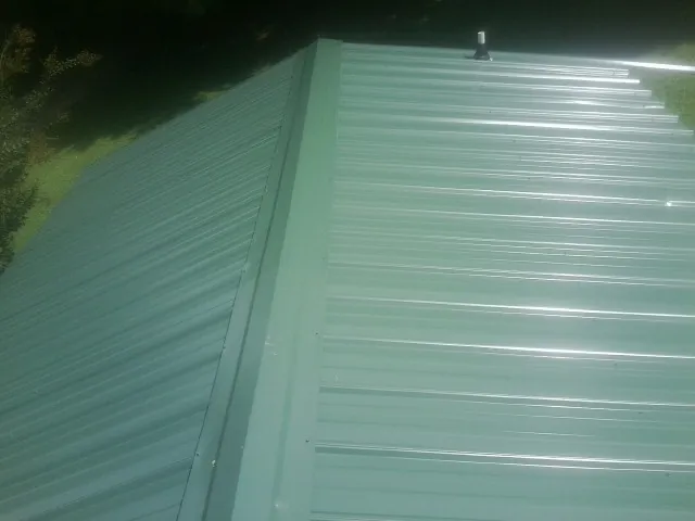 New green metal panels meeting at the ridge of a roof — Flat Roof Repair work by our crew in Bellvue