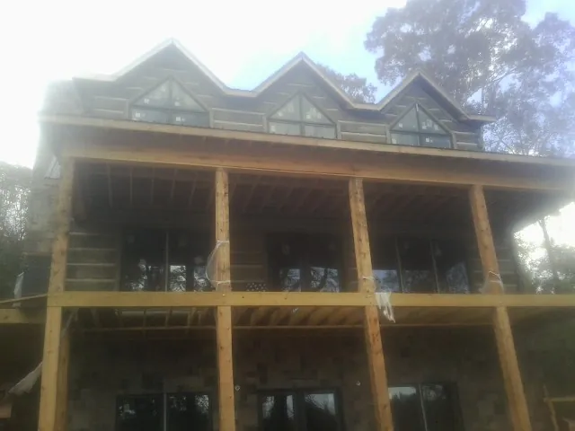 Dormers and porch framing on a large log home under construction — Roof Coating work by our crew in Bellvue