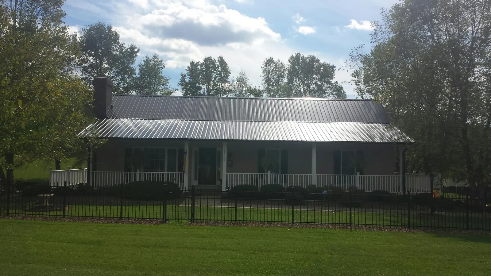 Gray metal roof on a brick ranch with a full width front porch — Gutter Guard Installation work by our crew in Bellvue