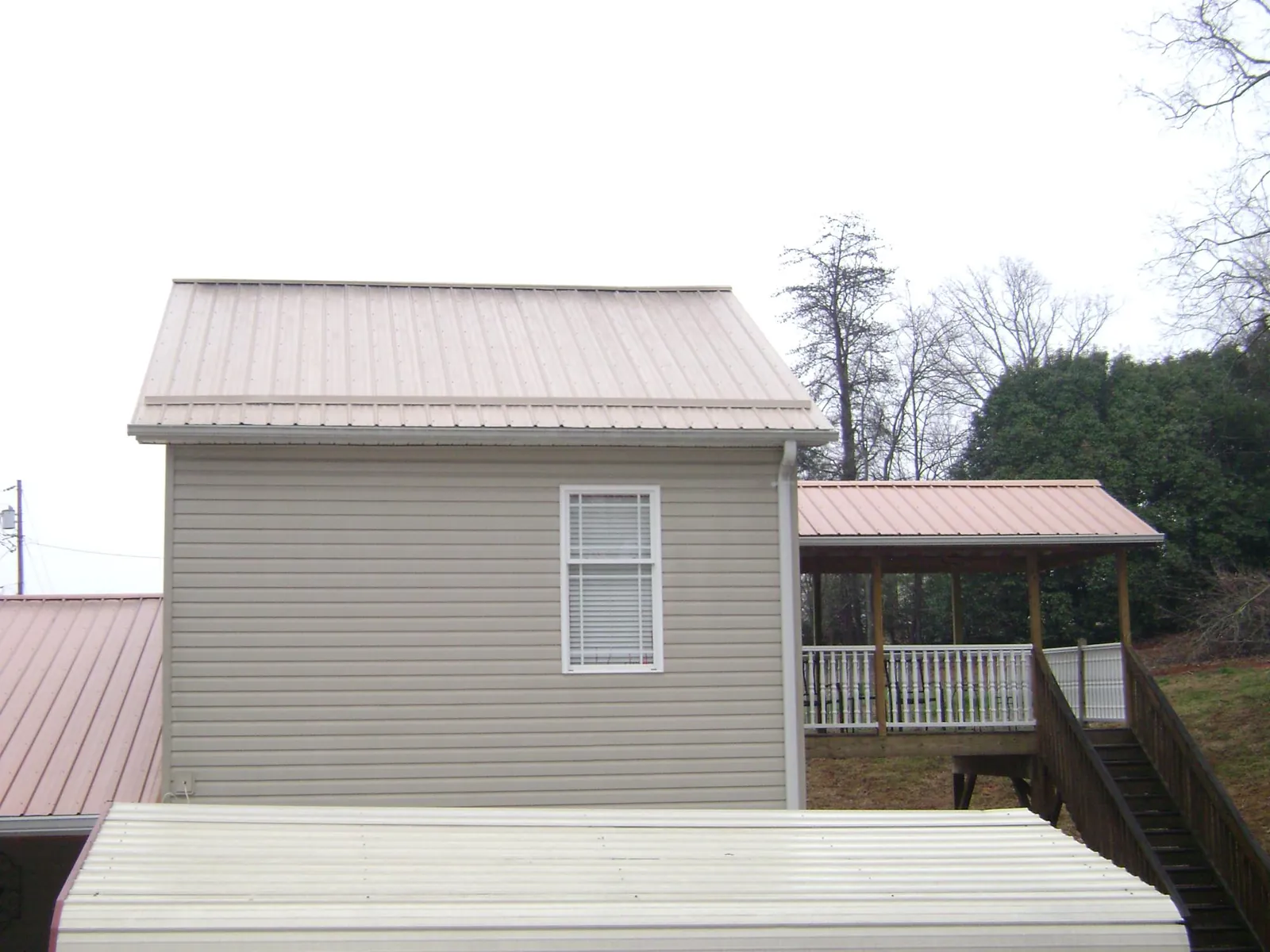 Tan metal roofs on a two story addition and attached porch, from a Roof Replacement job in Bellvue