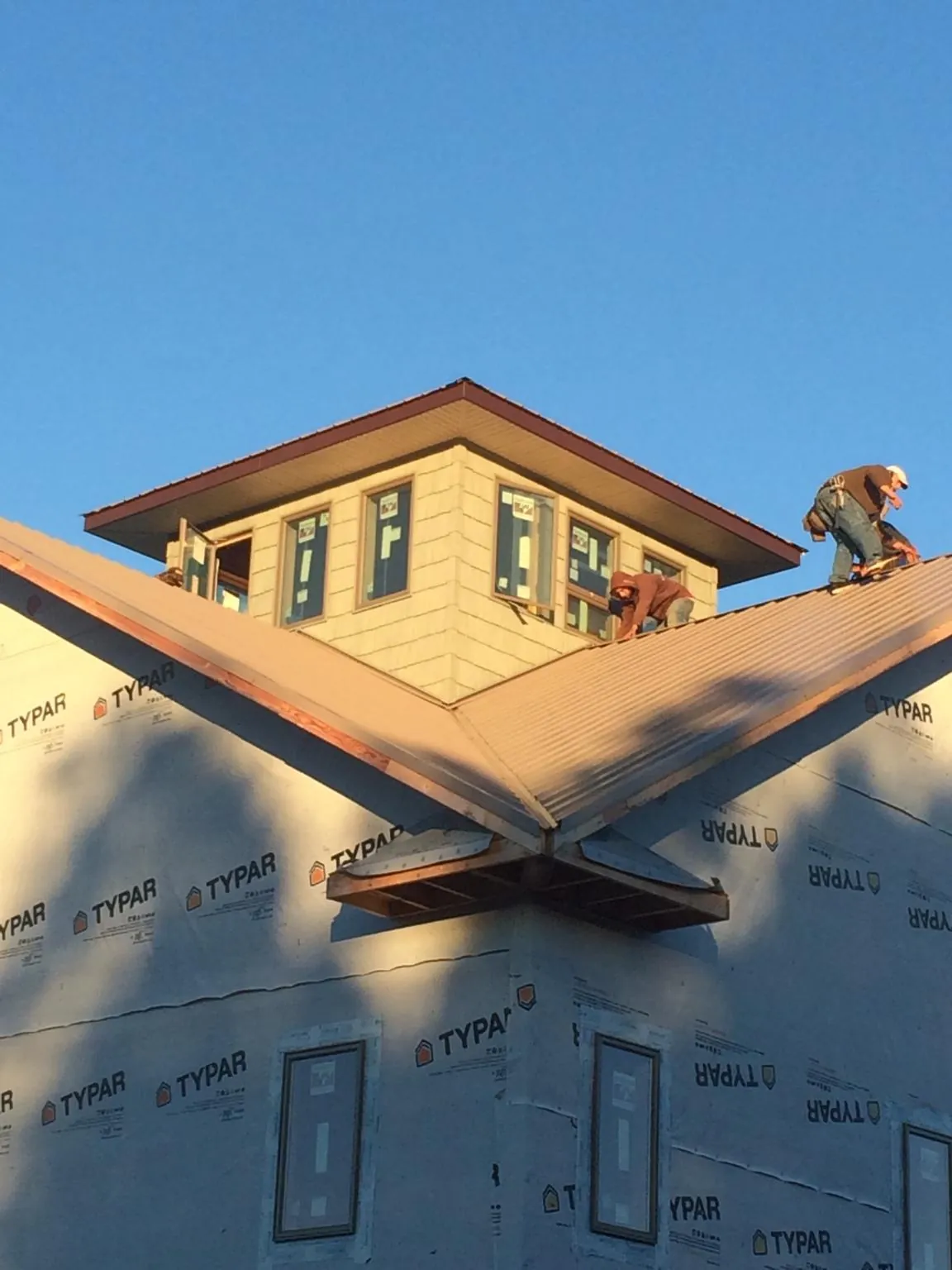 Roofers working around a rooftop cupola on a new metal roof at sunset — Roof Waterproofing in Bellvue by Roofing Brothers